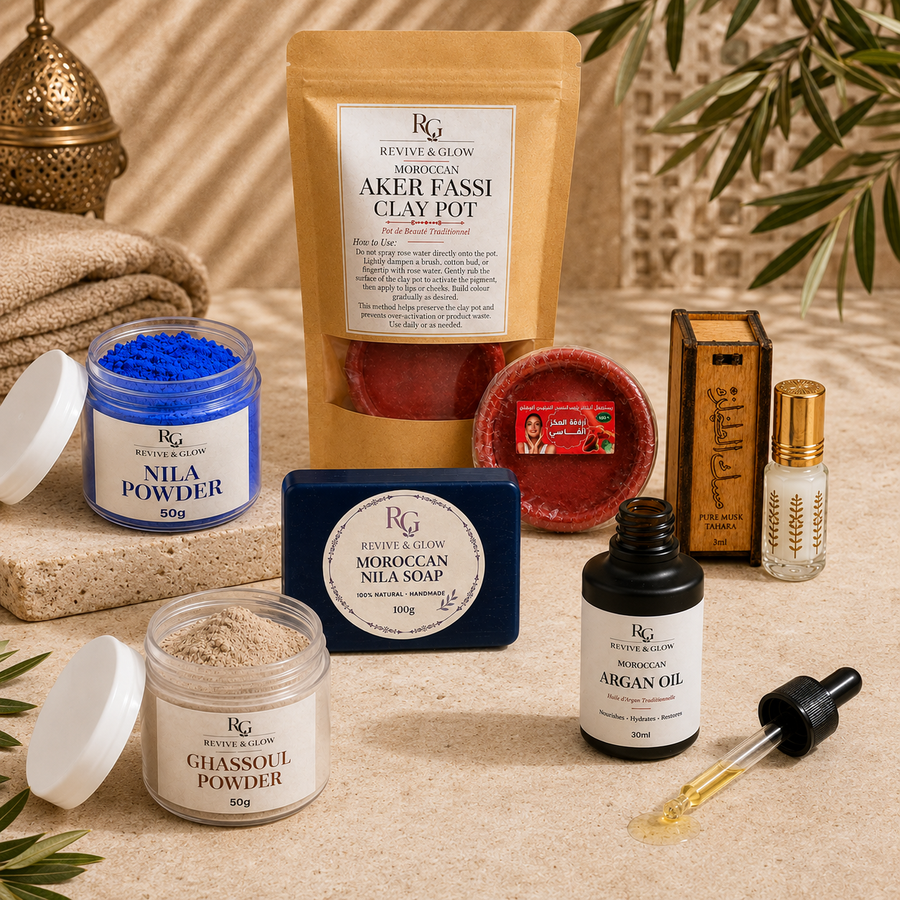 A Moroccan-themed skincare gift set from Revive & Glow, featuring a clay pot, jars of powder, soap, oil, and a wooden box, arranged on a beige textured surface with decorative props.