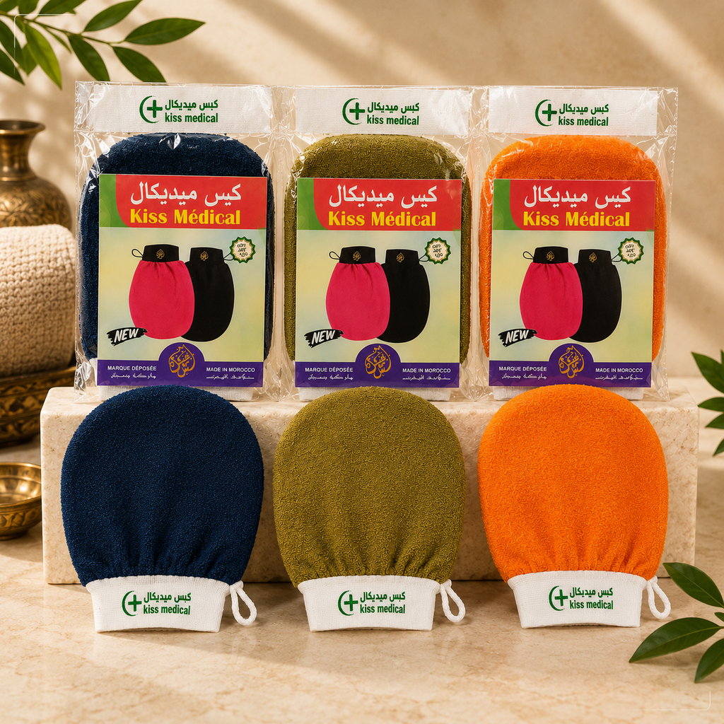 Three packaged Kiss Medical Kessa Gloves facial cleansing swabs in navy, olive green, and orange, displayed above their corresponding unpackaged swabs on a beige stone surface with decorative leaves and a brass vessel in the background.