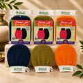 Three packaged Kiss Medical Kessa Gloves facial cleansing swabs in navy, olive green, and orange, displayed above their corresponding unpackaged swabs on a beige stone surface with decorative leaves and a brass vessel in the background.