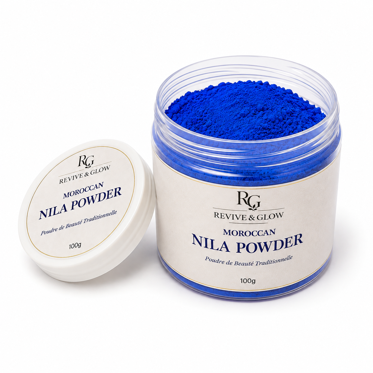 A clear plastic jar filled with vivid royal blue Moroccan nila powder, shown next to its white lid on a clean white background. The label reads 'REVIVE & GLOW MOROCCAN NILA POWDER' and indicates a weight of 100g.